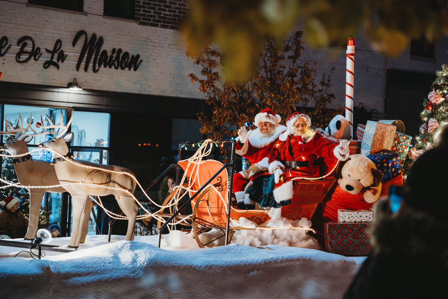 santa and miss claus riding on a sleigh in the parade