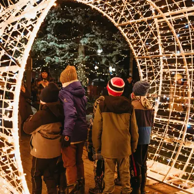 Group of kids getting picture taken under lit up Christmas ornament 