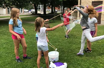 Children playing with bubbles on the grass outside the Woodstock Museum